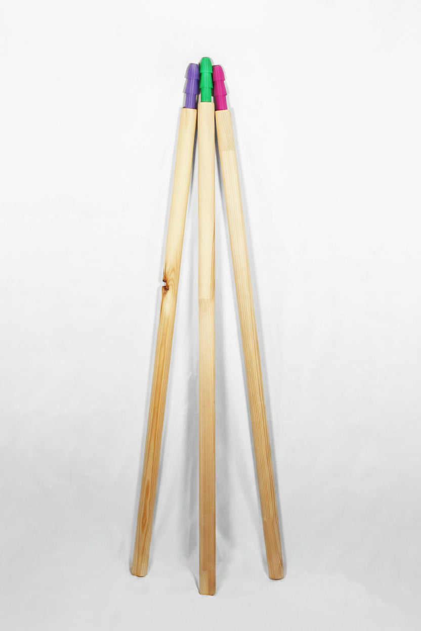Three poles standing upright in a V-shape arrangement, with colourful plastic tips in green, purple, and pink visible at the top, set against a plain white background.
